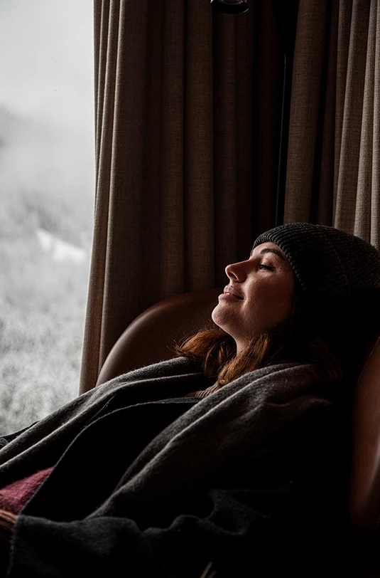 Frau entspannt am Fenster im Schnee