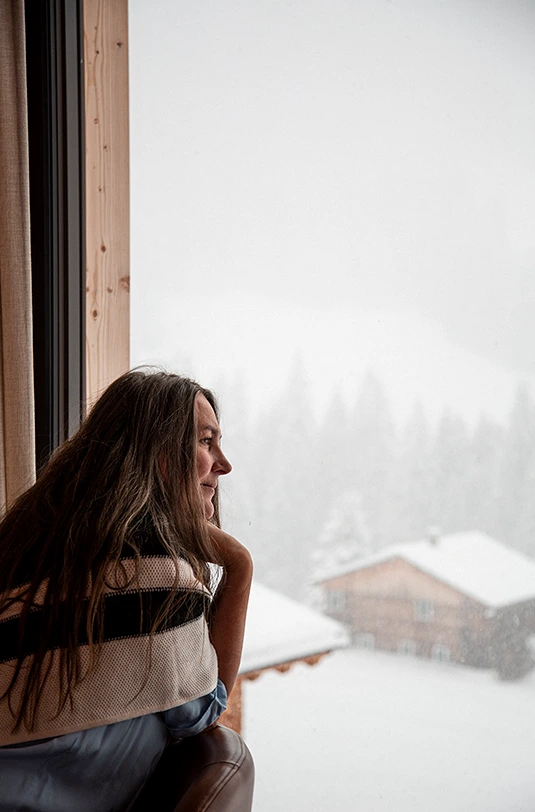 Frau schaut aus dem Fenster auf Schnee