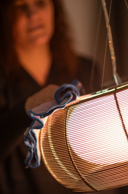 Frau reinigt eine hängende Lampe
