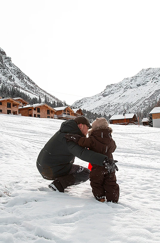 Vater spielt mit Kind im Schnee