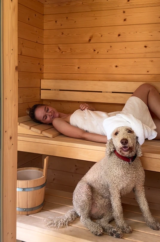 Frau entspannt mit Hund in Sauna
